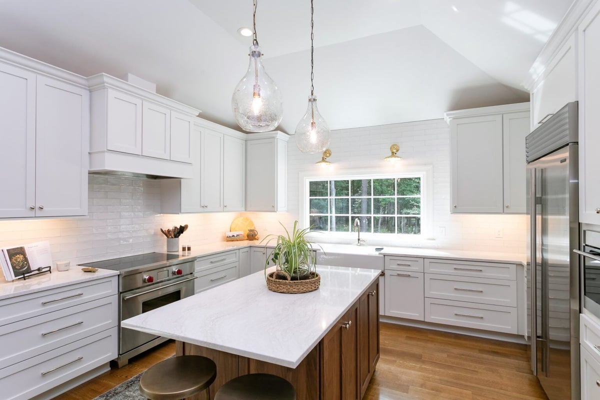 Bright and airy kitchen with white cabinets, glass pendant lights, and a wooden island in an Essex, Connecticut home