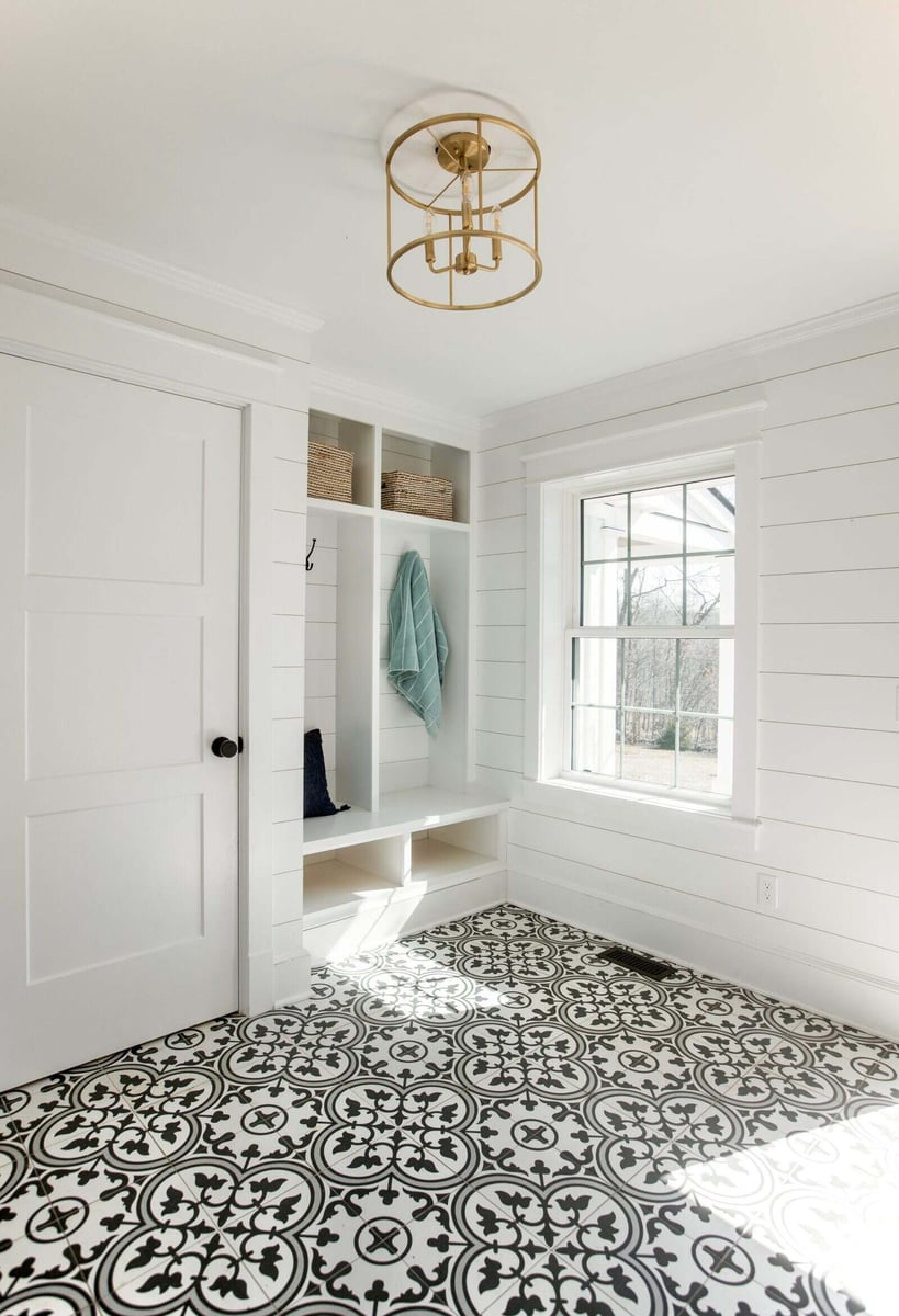 Bright mudroom with custom storage and decorative tile floor in an Essex, Connecticut farmhouse by Craft Design + Build