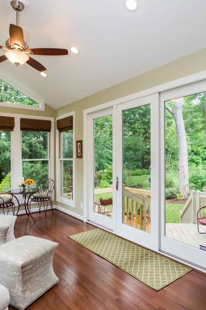 Bright sunroom with a view of lush greenery and comfortable seating in Essex by Craft Design + Build