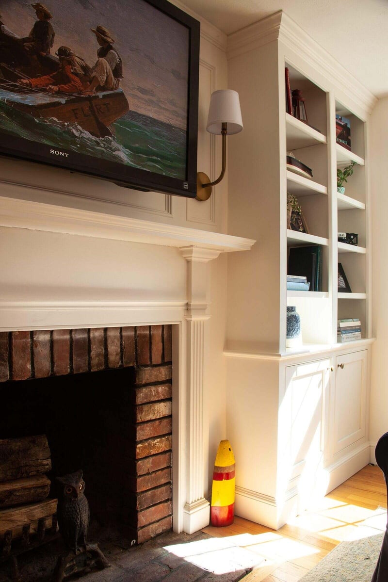 Close-up of a brick fireplace with a painting above it in a custom living room in Essex, Connecticut by Craft Design + Build