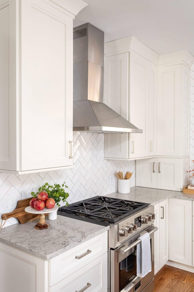 Close-up of remodeled kitchen in Essex, Connecticut with white cabinets and herringbone backsplash by Craft Design + Build