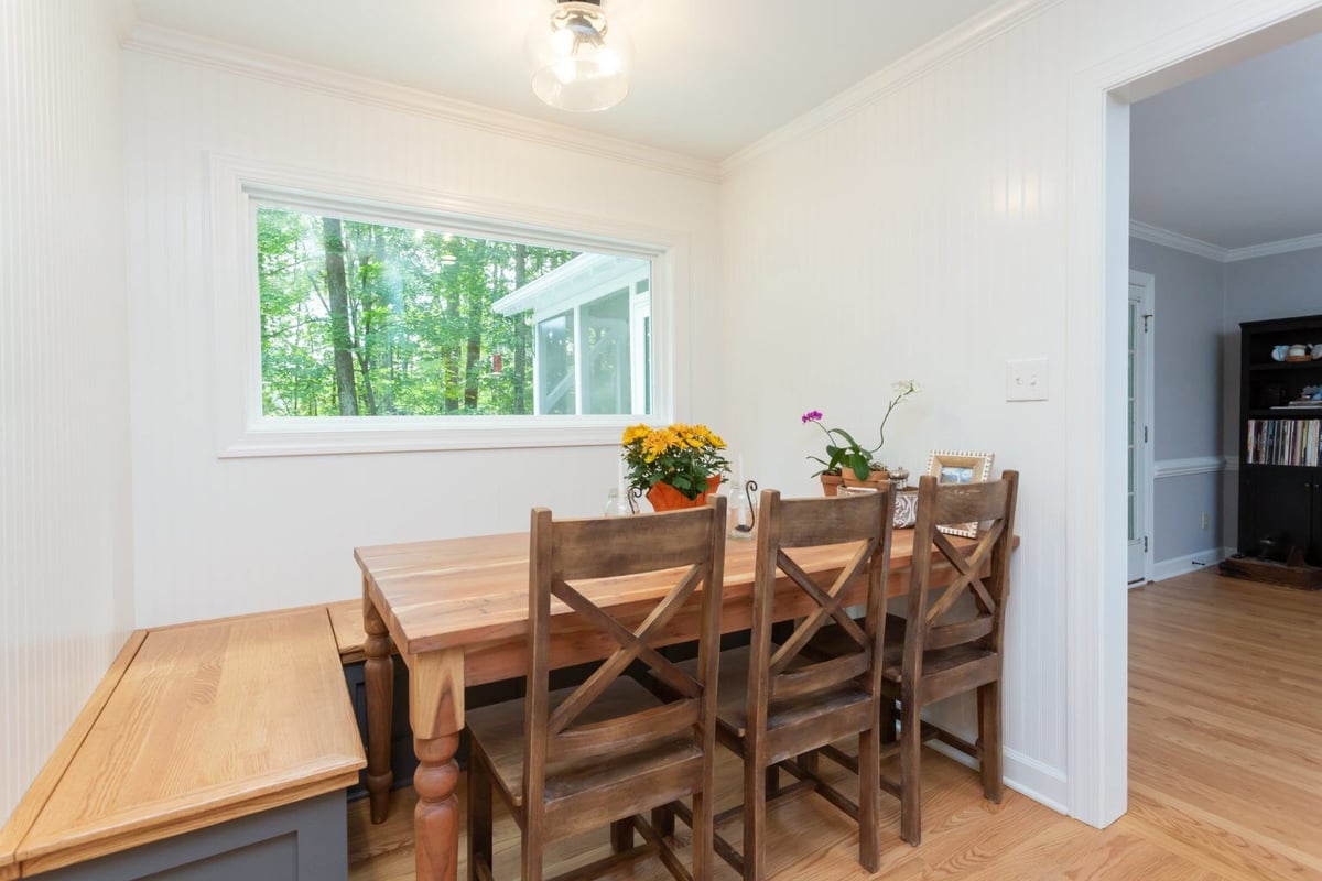 Cozy dining nook with wood furniture in a remodeled Essex home by Craft Design + Build