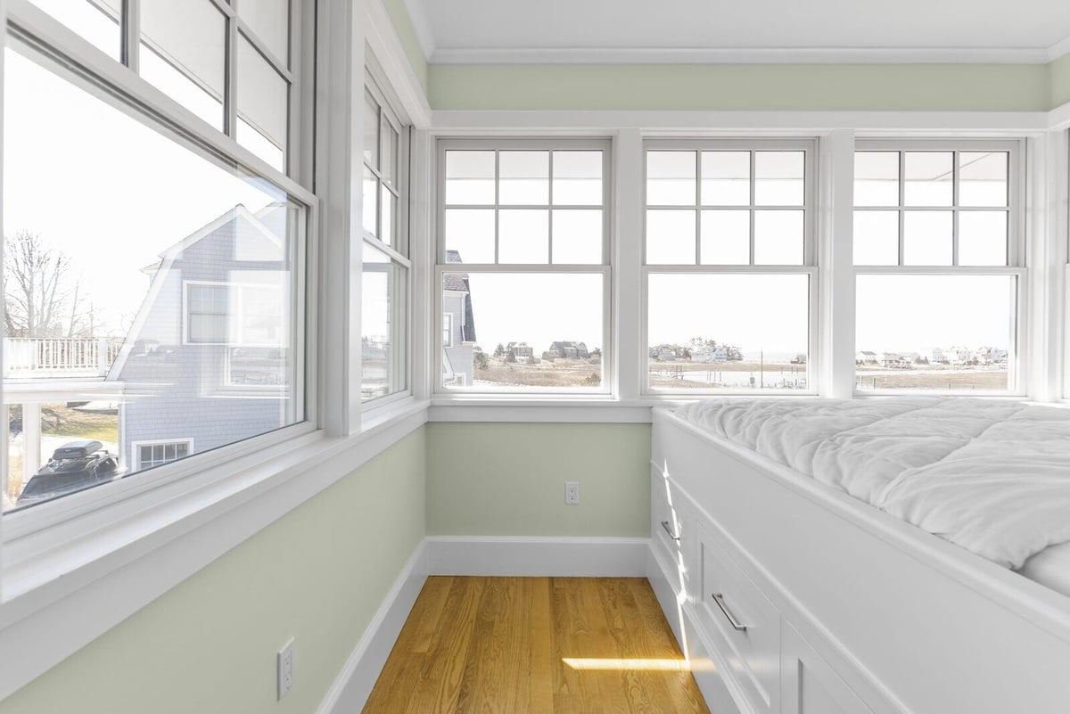 Custom-built bed with storage drawers next to large windows in Essex, Connecticut, designed by Craft Design + Build-1