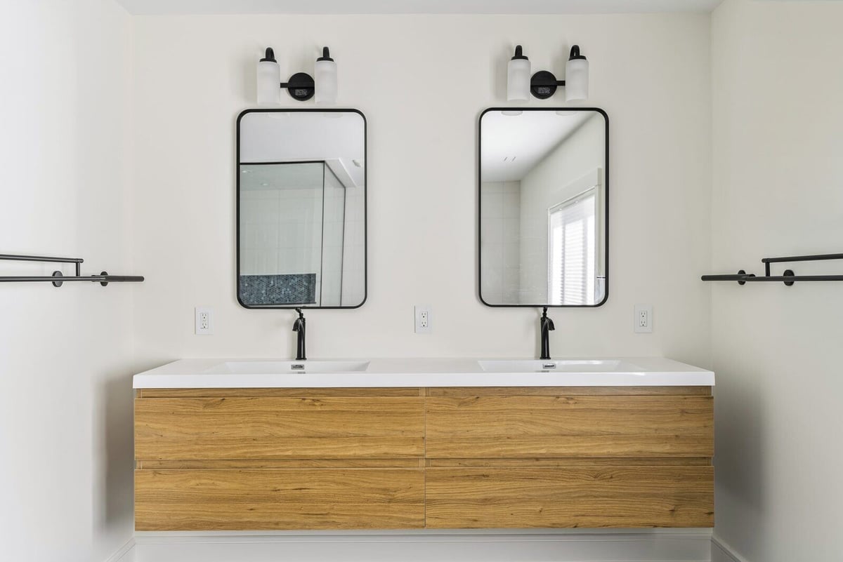 Double vanity with wooden cabinets and black-framed mirrors in a Killingworth bathroom, designed by Craft Design + Build, Essex, Connecticut