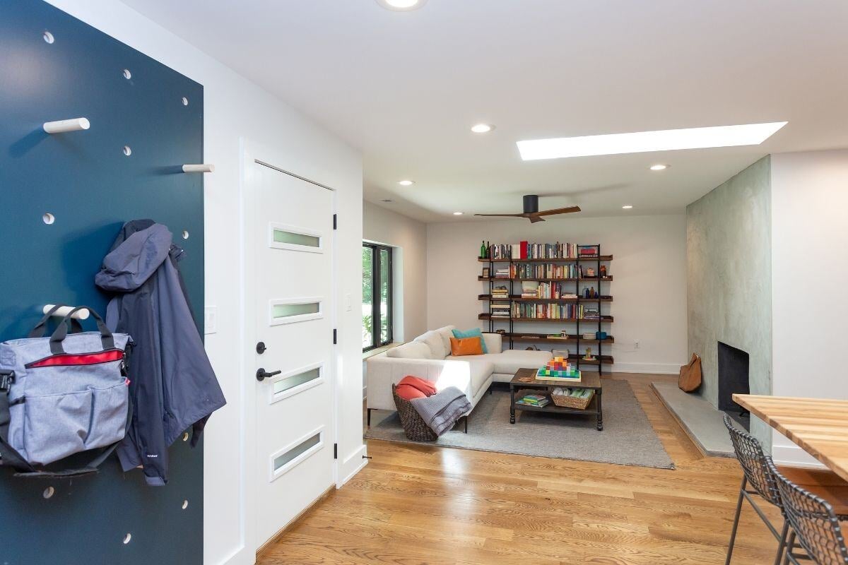 Entrance to modern living room with bookshelf and fireplace, part of a home renovation by Craft Design + Build, Essex, Connecticut