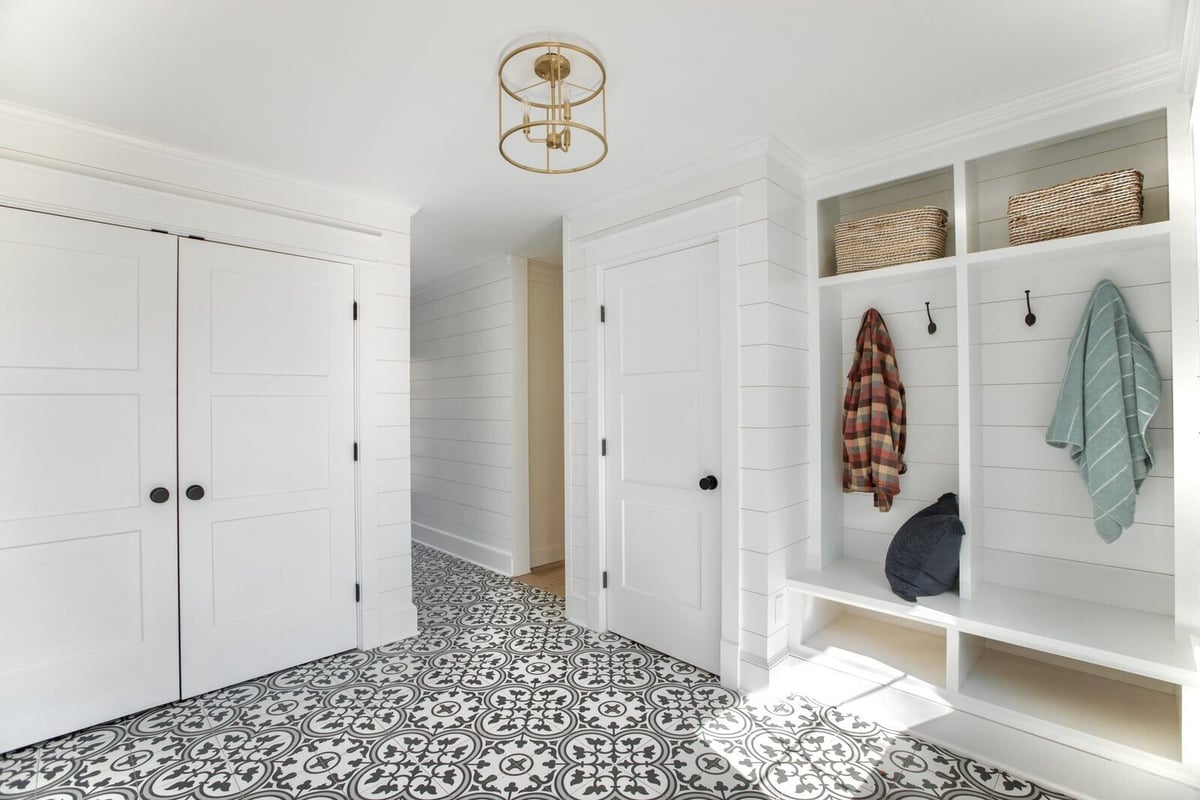 Farmhouse-style mudroom with built-in cubbies, shiplap walls, and a bright, patterned tile floor in Essex, Connecticut