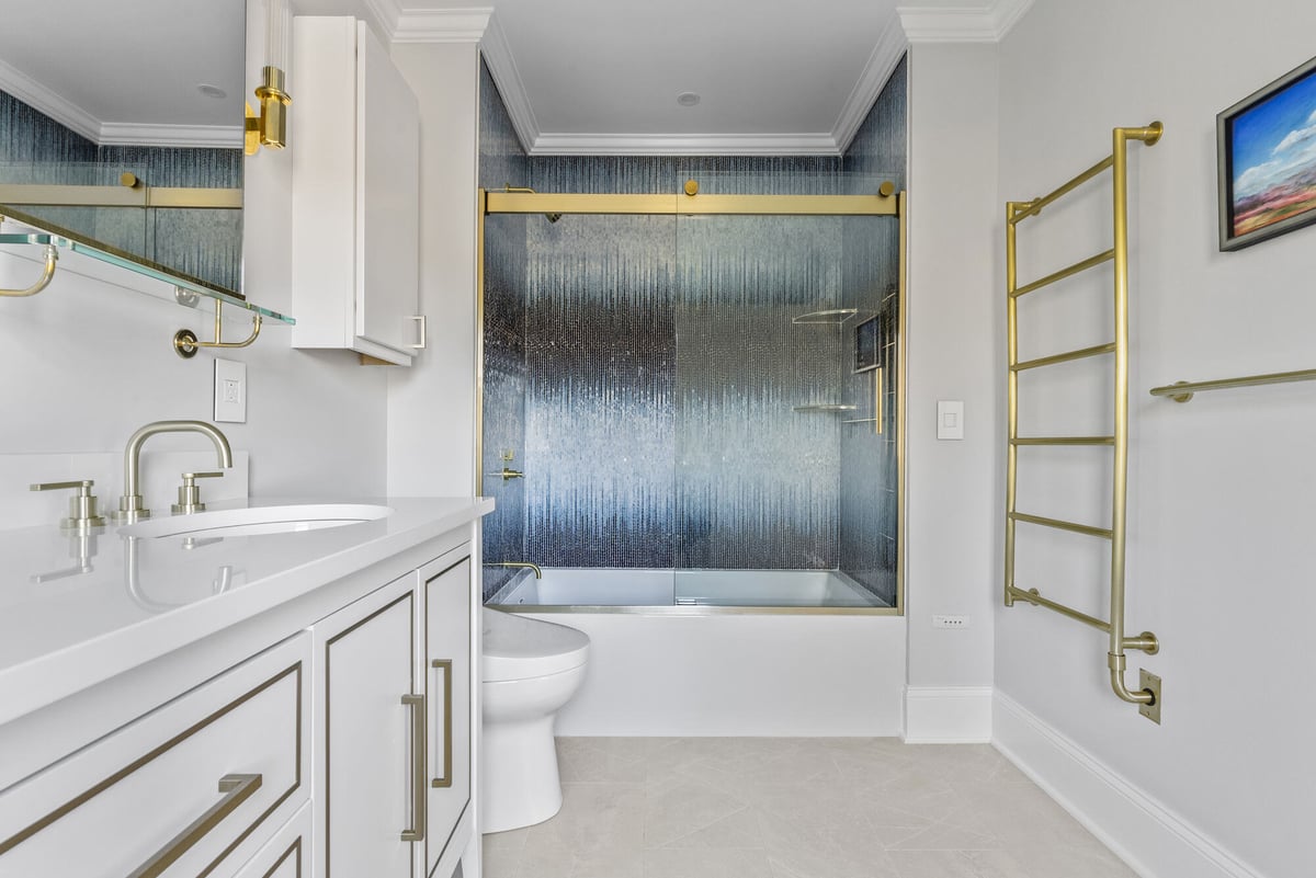 Stylish bathroom remodel with white cabinetry and gold accents by Craft Design Build in Essex, CT