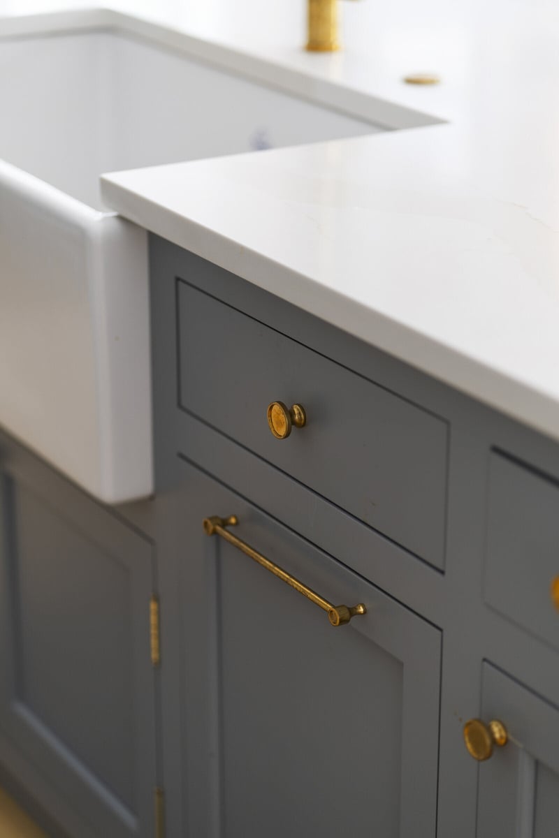 Close-up of grey kitchen cabinets with gold handles, remodeled by Craft Design and Build in Essex, Connecticut