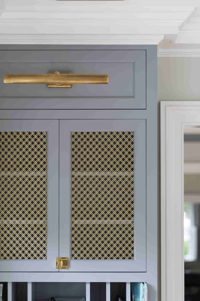 Grey cabinets with gold mesh detail in a remodeled kitchen by Craft Design and Build in Essex, Connecticut