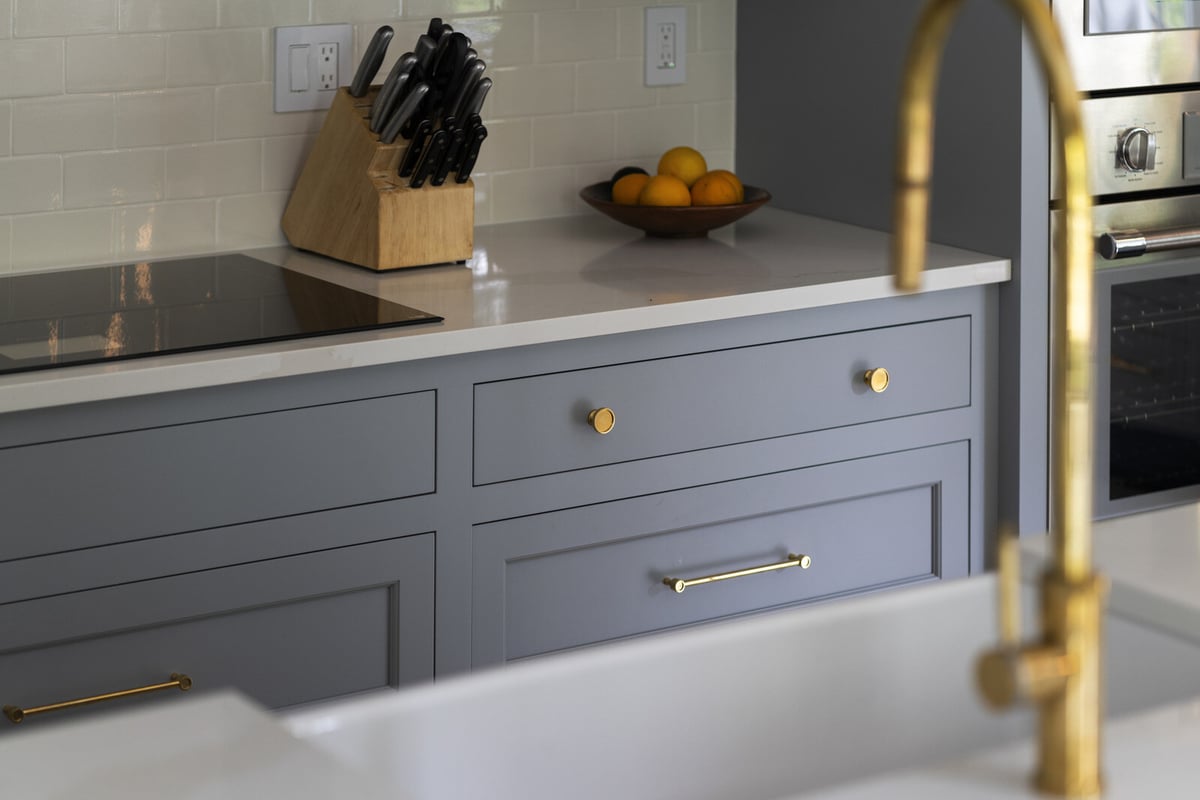 Kitchen countertop with a gold faucet and knife block, remodeled by Craft Design and Build in Essex, Connecticut