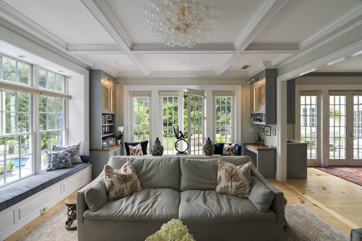 Modern living room with large windows and a cozy sofa, designed by Craft Design and Build in Essex, Connecticut