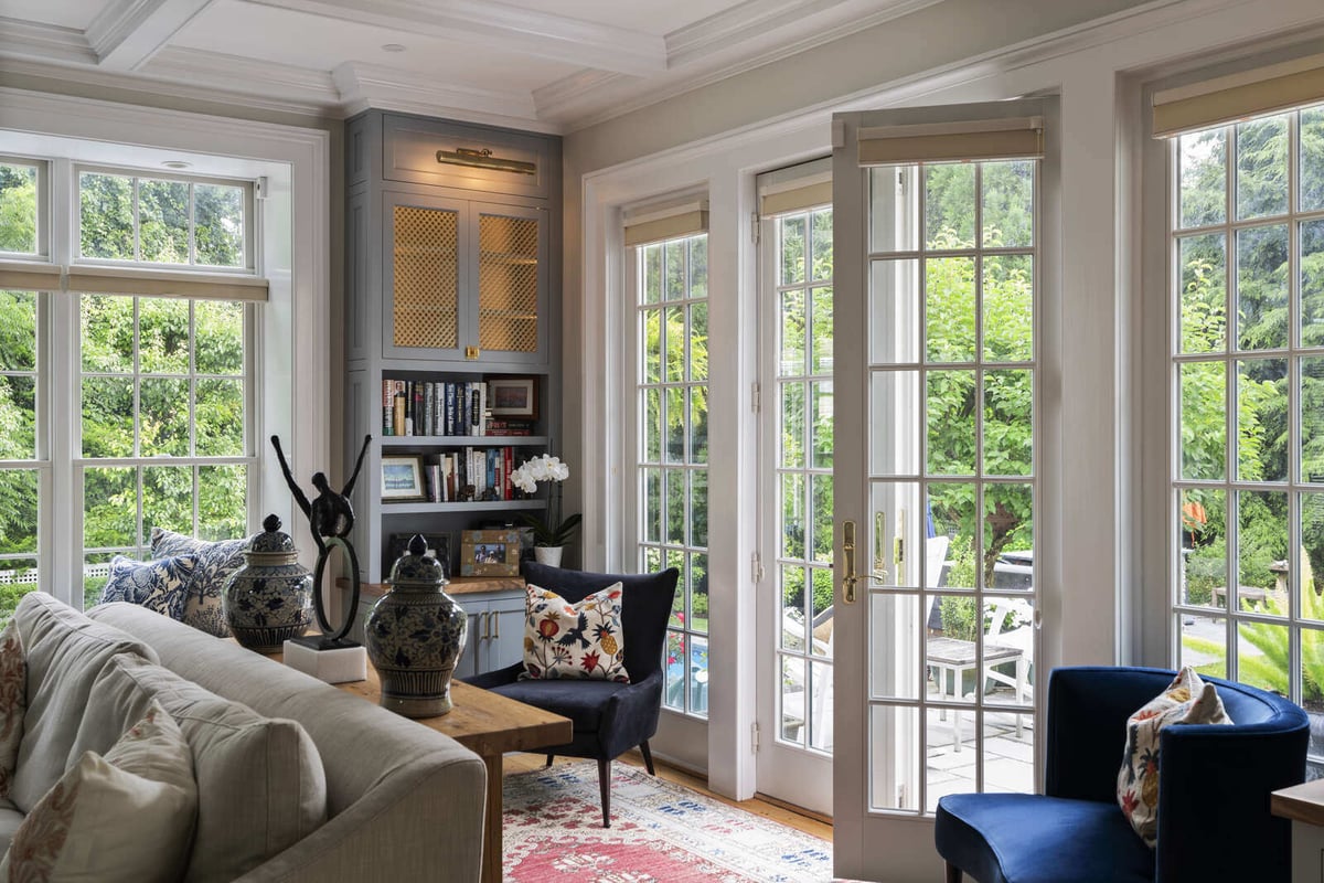 Open-concept living and kitchen area by Craft Design and Build in Essex, Connecticut, featuring French doors and grey cabinets