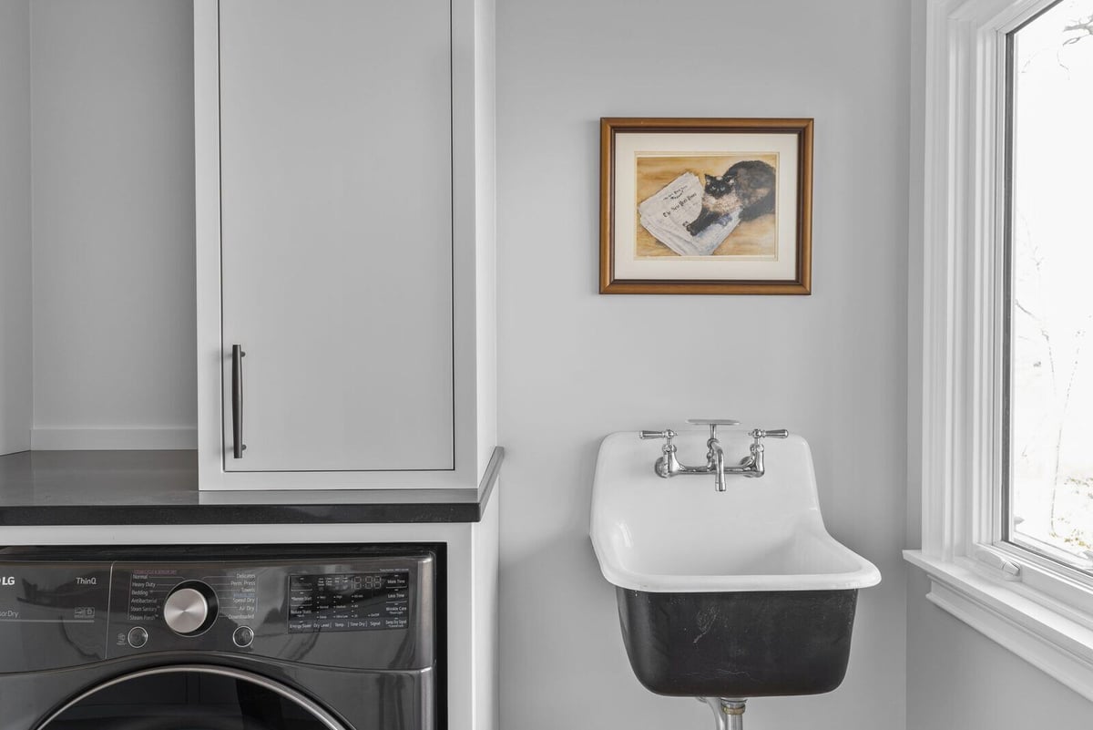 Functional Essex laundry room featuring white cabinets and sink, remodeled by Craft Design + Build, Essex Connecticut