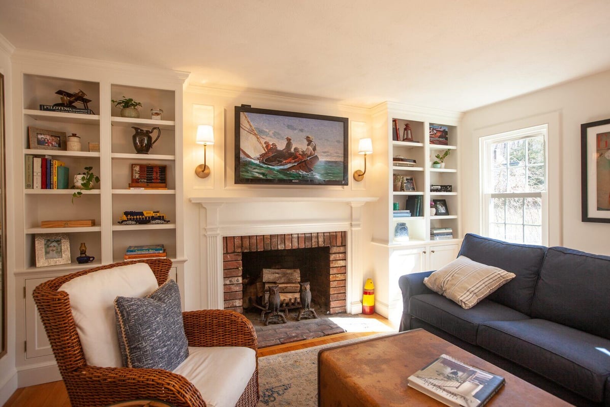 Living room in Essex, Connecticut with a brick fireplace and custom shelving, remodeled by Craft Design + Build