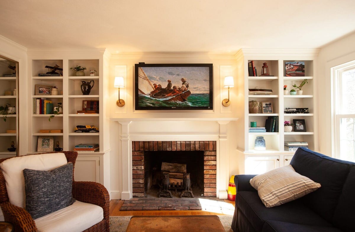 Living room with a brick fireplace and built-in shelving in a custom home in Essex, Connecticut by Craft Design + Build