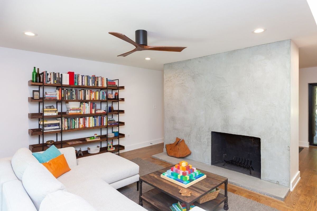 Living room with minimalist bookshelf and modern fireplace, part of a whole home renovation by Craft Design + Build, Essex, Connecticut