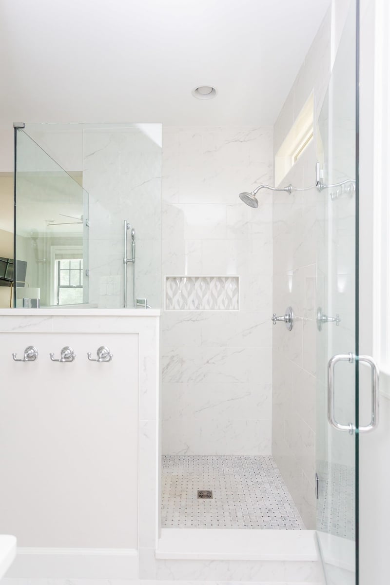 Luxurious marble shower with glass enclosure in an Essex, Connecticut home, renovated by Craft Design + Build