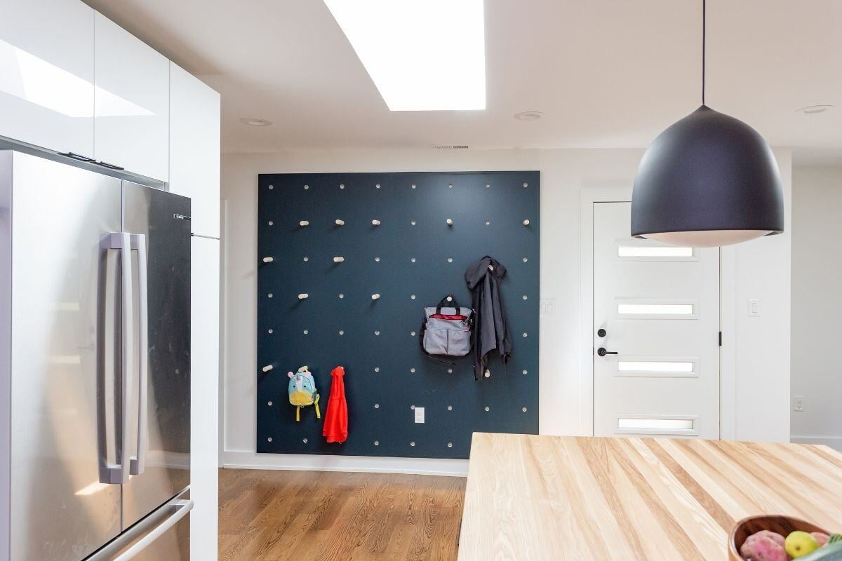 Modern kitchen with pegboard wall and natural light in a custom renovation by Craft Design + Build, Essex