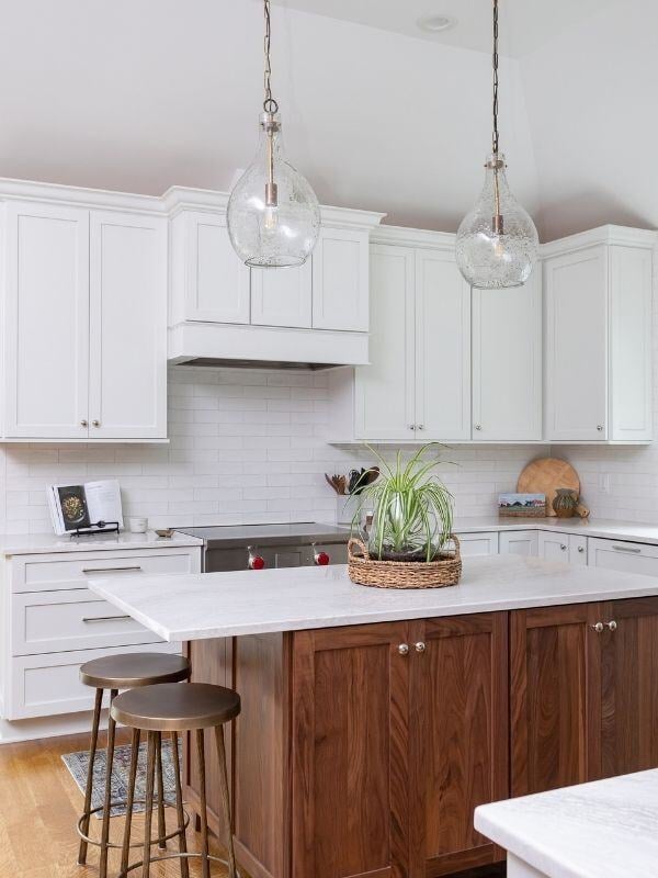 Modern kitchen with white cabinetry and walnut island, featuring pendant lighting, in a South Raleigh home renovation by Craft Design + Build