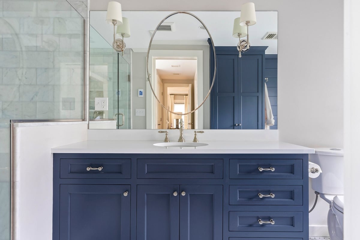 Navy blue vanity with oval mirror in a remodeled bathroom, Essex, Connecticut