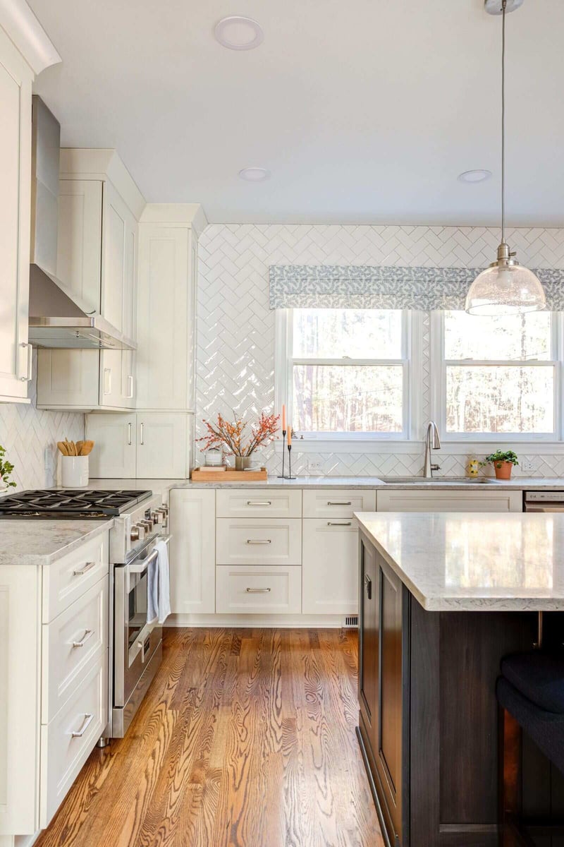 Renovated kitchen with large windows and white cabinets in Essex, Connecticut by Craft Design + Build