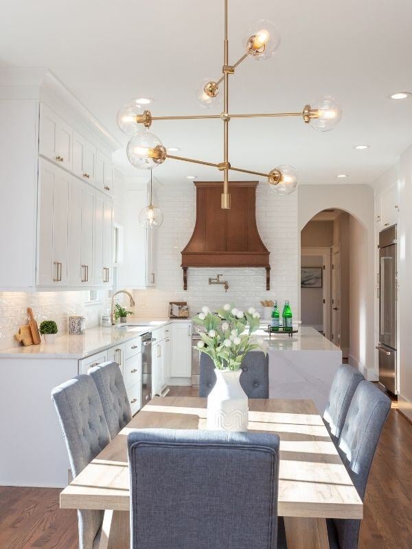 Renovated kitchen with white cabinetry and a modern chandelier, designed by Craft Design + Build in Essex, Connecticut