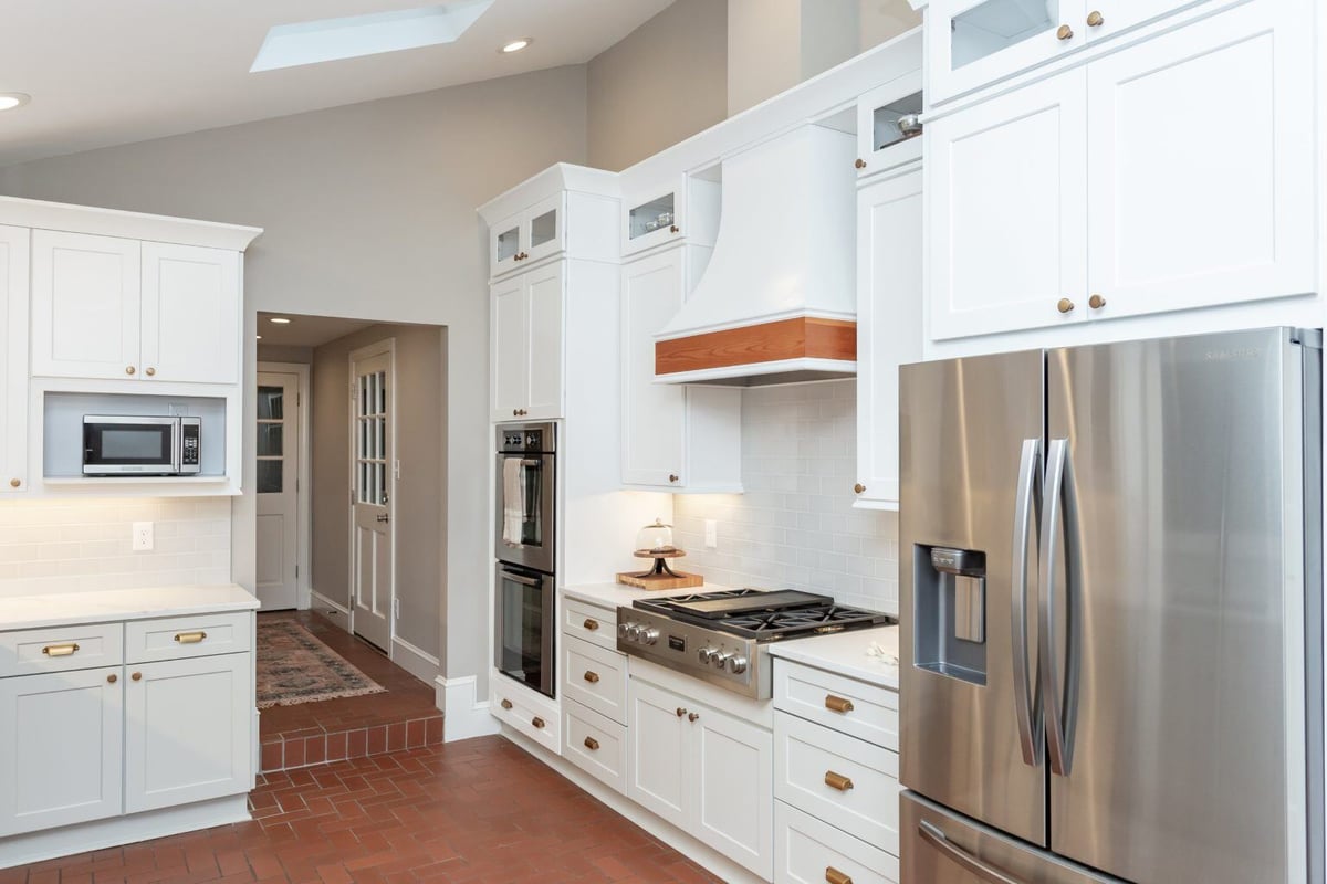 Renovated kitchen with white shaker cabinets and stainless steel accents by Craft Design + Build in Essex