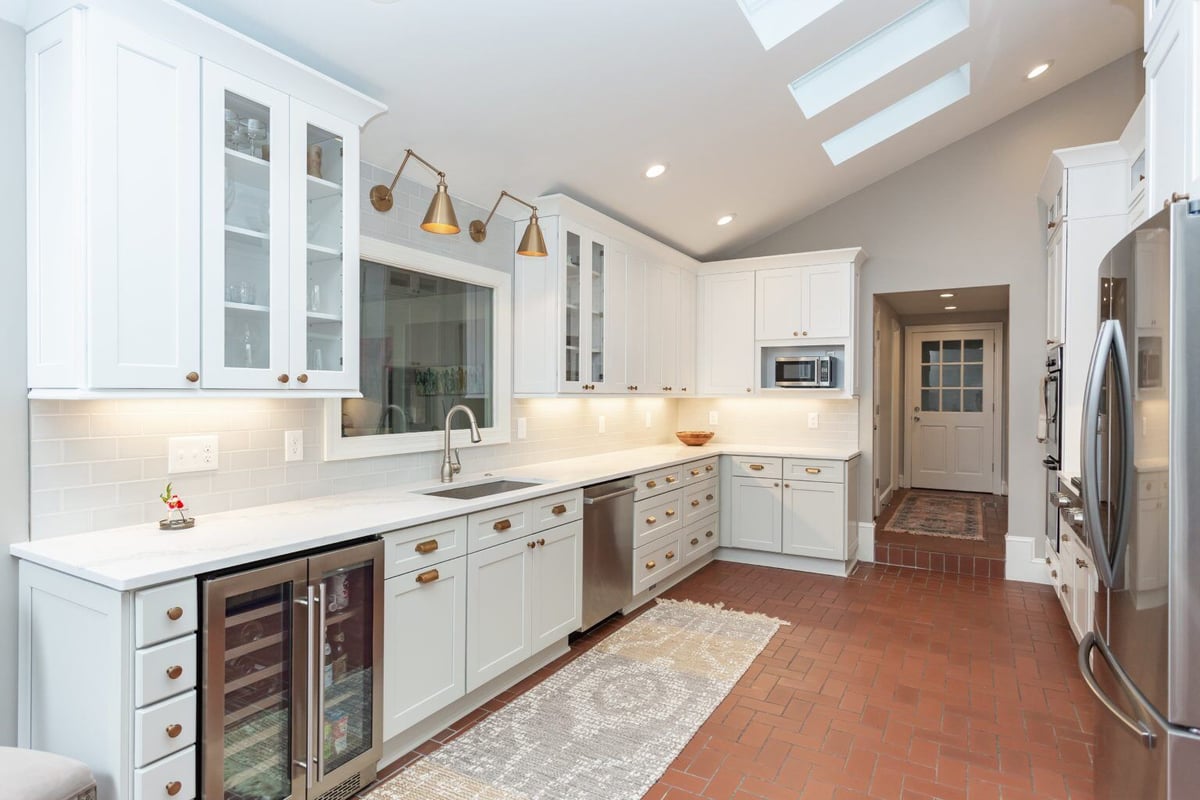 Spacious renovated kitchen with white cabinetry and skylights in Essex by Craft Design + Build