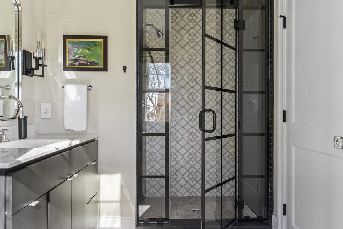 Stylish glass shower door with black grid design in Essex home renovation by Craft Design + Build, Essex Connecticut