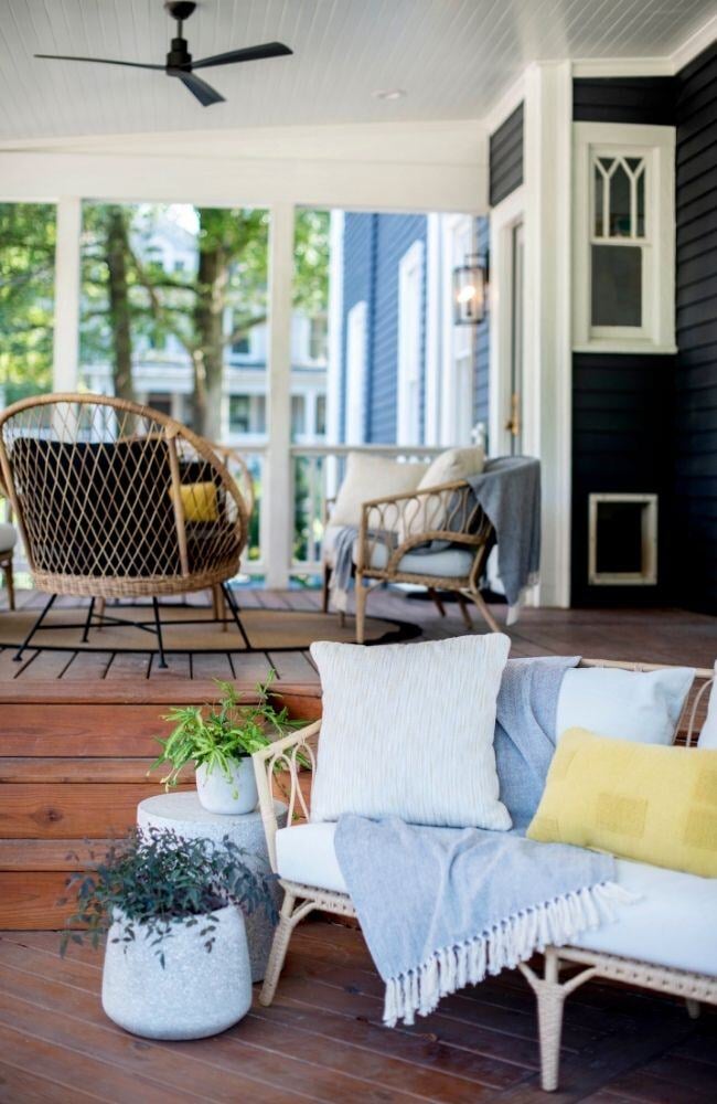 Stylish porch with wicker furniture and wooden flooring in an Essex, Connecticut historical home renovation by Craft Design + Build