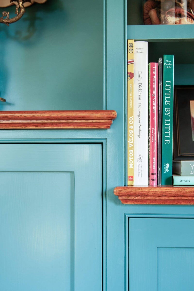 Teal cabinet with wood trim and a row of books in a detailed view of a Chester home renovation